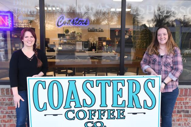 Sara Johnson (right) and Kandi Slocum hold up the sign to Coasters Coffee Co. outside the shop. Johnson stated she would transfer the business to employee and friend Kandi Slocum in early January.