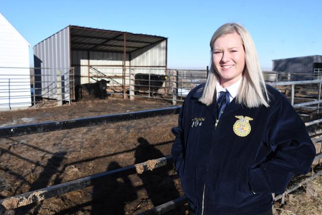 Hampton senior Brooke Lubke stands near the Hawk Herd pen behind the school. “It sounds crazy to say I get to see a cow at school, but it is really amazing to see that,” she said.