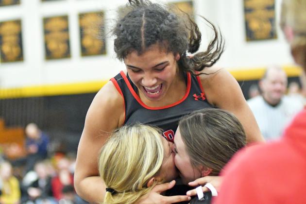 Aurora’s Kehlanee Bengtson leaps into the waiting arms of her coaches, Sheri Thompson and Bailly Ballard, after winning an individual district wrestling championship Saturday in Fremont. 