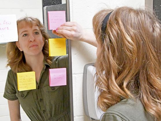 Aurora High School custodian Maddy Barnes places notes of encouragement on the mirror of the girls restroom. The sticky note project is just one way the young staff member makes connections and serves as a role model to students and staff.  