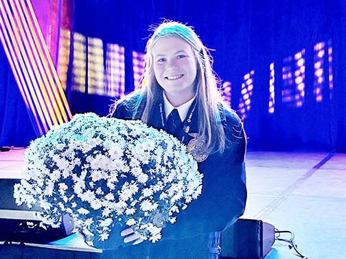 Morgan Bonifas holds a pot of her mums near the stage at the national FFA Convention in Indianapolis earlier this month, where she was recognized as one of the four national finalists in FFA proficiency in the area of specialty crop production and entrepreneurship.