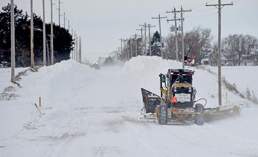 Two motor graders equipped with v-plows continue to work Monday afternoon to open up a two-mile stretch of 12 Road just east of Aurora. The process had started at 7 a.m. and by 1:30 p.m. only a one lane track had been cleared. 