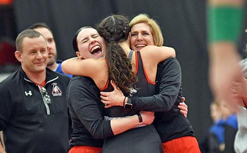 Aurora senior Natalie Bisbee embraces her coaches Bailly Ballard (left) and Sheri Thompson after winning her heartbreak round match Friday night to become a three-time state qualifier.