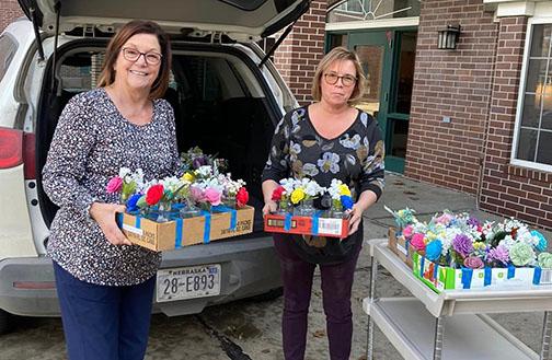 Nancy Ronnau (left) delivers 48 wooden flowers to activities director Nicole Nelson at East Park Villa. Ronnau also delivered an additional 115 flowers to residents at Memorial Community Care and Westfield Quality Care in Aurora in time for Valentine’s Day.
