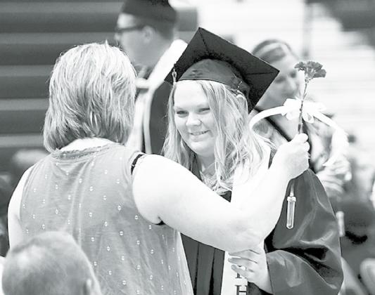 Hampton senior Logan Nissen presents a flower to her mother, Amy, during Saturday’s graduation ceremony. News-Register/Kurt Johnson