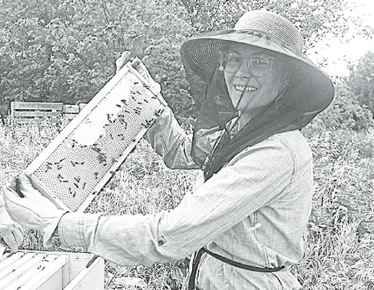 Megan Vetter holds up a frame filled with honey from one of her hives. News-Register/Jeni Moellenberndt