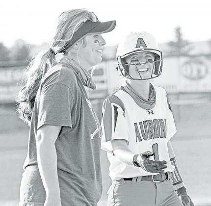 Aurora senior Kylie Larson shares a light moment with Aurora coach Ashton Voss after sliding safely into third base during the Lady Huskies’ 10-3 win over Holdrege Thursday. News-Register/Richard Rhoden