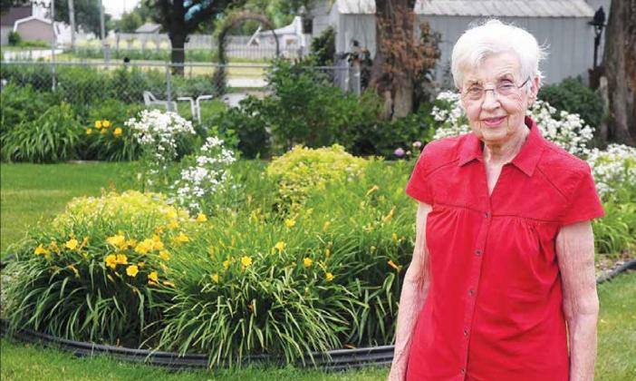 Pollie Hahn stands in front of her berm. The center piece of her garden has been filled with a variety of flowers in all shapes, sizes and colors. News-Register/Jeni Moellenberndt