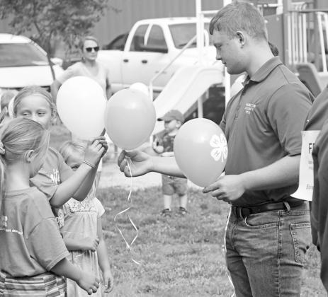 Brekyn Papineau hands out balloons to some youngsters that were released just before the swine show Saturday in honor of Nicholas Pachta. News-Register/Richard Rhoden