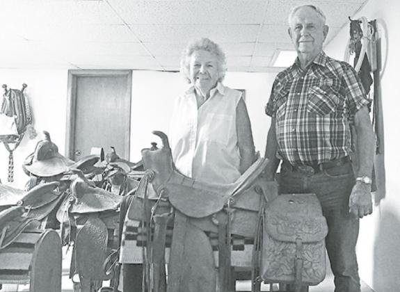Elvera and Dwight Willcock stand with his favorite saddle among his collection. This saddle was a gift from his uncle and was used until they sold their last working horse. News-Register/Jeni Moellenberndt