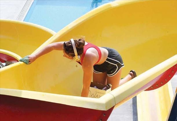 Lifeguard Jadyn Cattau puts a layer of wax on the slide Monday morning in preparation for Saturday’s opening of the Aurora Aquatic Center. News-Register/Kurt Johnson