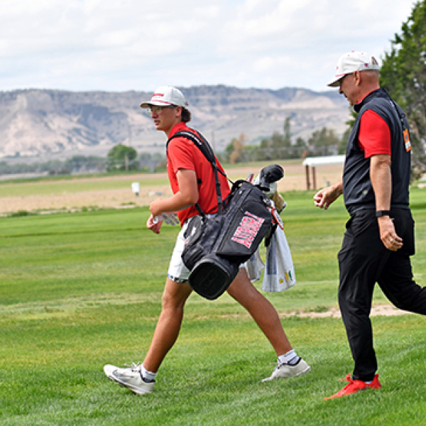 Cash Garrett walks off the No. 11 tee box at Scottsbluff Country Club with the Bluffs in the background and coach Craig Badura in tow. 