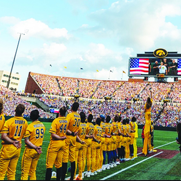 Aurora choir teacher Jason Frew, shown on the large scoreboard, performed the National Anthem during the Savannah Bananas baseball game at Kinnick Stadium in Iowa City July 4.