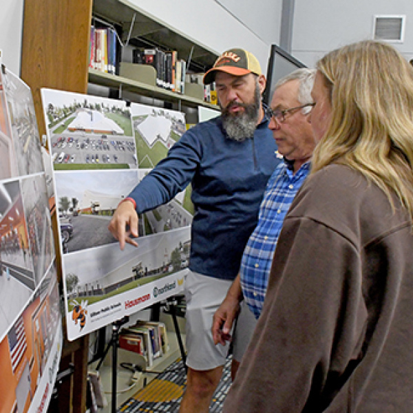 School board member Brandon Hunicutt (left) goes over diagrams of the project with community members Gene Consbruck (center) and Jordan and Jake Findley.