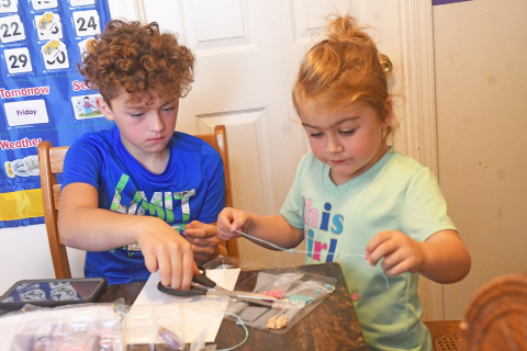 Keagen and Emmah White work on a bracelet making kit together. In front of them is a seed tray that Emmah has started working on.