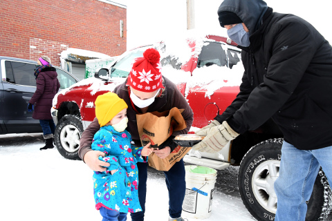 Hamilton County Food Pantry volunteer Craig Ratzlaff offers a pie to a young girl and her great-grandmother as part of the annual holiday meal food distribution event Saturday.
