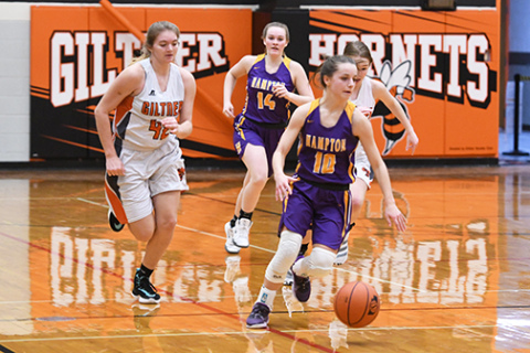 Hampton senior Lexi Wolinski hustles the ball up court in transition, while Giltner senior Alice Wiles (left) follows the play.
