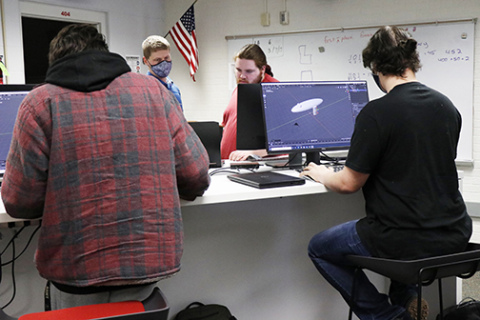 Jericho Stack (left), teacher Dustin Broeder, Logan Bennett and Brandon Krunovsky puzzle out a few pieces of their large project during Monday’s class. 