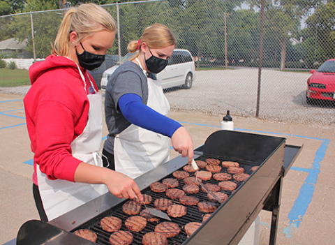 Brianna Wilshusen (left) and Aubree Quast work together to grill up hamburgers for HPC students.