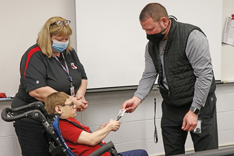 Paraeducator Roxie Obermier (left) helps motivate student Tanner Davison to punch AHS business teacher Dana Thompson’s Husky Grind punch card.