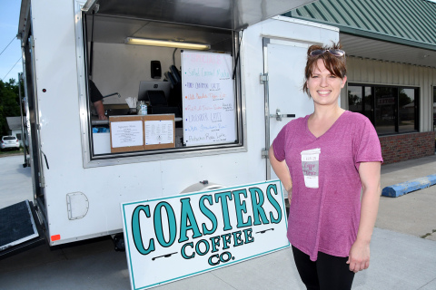Sara Johnson stands by a trailer she is using as the temporary home of Coasters Coffee Co. Her business will move soon into the newly renovated space in the background, located at 1003 Q St., by the Aurora Wash House and Verizon.