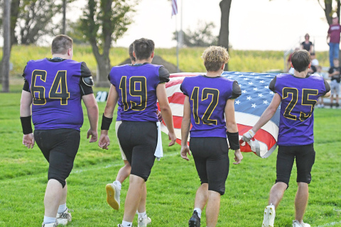 Fans on both sides of the field Friday in Hampton paused in silent tribute as senior Hawk football players carried an American flag across the field to be raised in honor of the 9/11 anniversary. Carrying the flag are from left: Michael McFarlane, Tyson Wolinski, Justin Gyhra and Austen Adams.