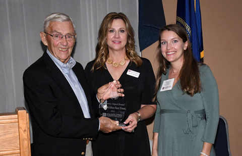 Jim Koepke, left, and Emily Jasnowski, right, accept the Community Impact Award from Tammy Morris, executive director of the Hamilton Community Foundation. 