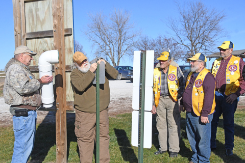 From left, Dick Berthold, Harold Fankhauser and members of the Aurora Lions Club work to install a fishing line recycling bin near the water’s edge at Pioneer Trails Lake northeast of Aurora.