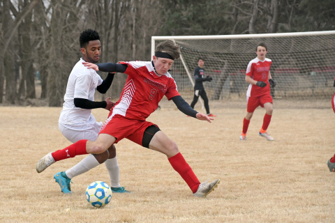 Aurora’s Zander Stromer looks to block off a Schuyler player during the Huskies’ 4-0 loss to the Warriors Thursday. 