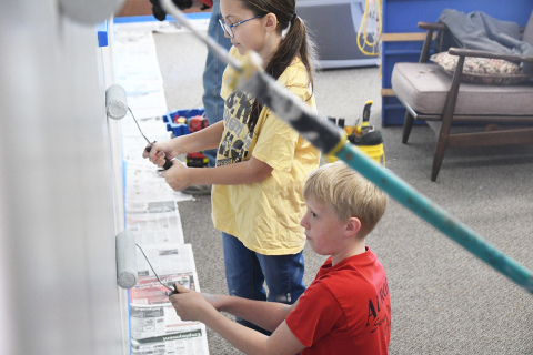 Clarissa Orman and Wyatt Philippi help adults paint the wall of the Youth Center. Children have offered both help and insight into the center’s renovation.