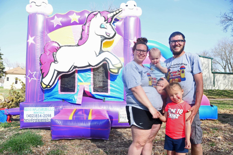 From left, Tessa, Hudson, Lyla and John Beck pose in front of the inflatable unicorn-themed bouncy house in their backyard. The family moved their business to Marquette after starting it in Kenesaw back in 2019. 