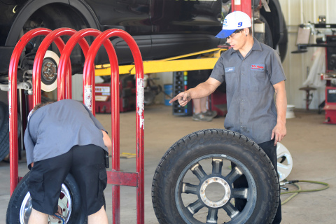 Mechanic Josh Moellenberndt (right) points out something to Blake Delarnn as they change out the tires on a state patrol vehicle in the background. Common parts like tires can now take days to arrove, while hard parts can take weeks up to a month.