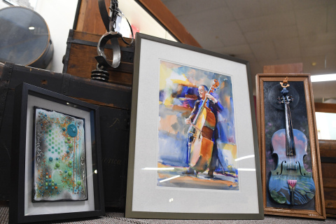 Some of the artwork that will be displayed in the Plainsman Museum from Aug. 30 to Sept. 30 as part of Impact Nebraska Artists ‘Color of Music-Rhythm of Art’. Left to right: “Mozart’s Summer Orchestra” by  Jerene Kruse made of fused glass, “Lyrical Cadence” by Beth R. Jasnoch made of metal, “Symphonic Connection” by Ken Hosmer which is a watercolor painting and “Concerto to a Grand Adventure” by Jana Van Housen which is an assemblage made, in part, from a violin from a Goodwill.