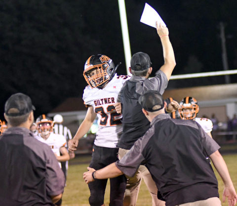 Giltner's Kale Bish celebrates with the Hornet coaches after a 38-6 win over Deshler Friday night. 
