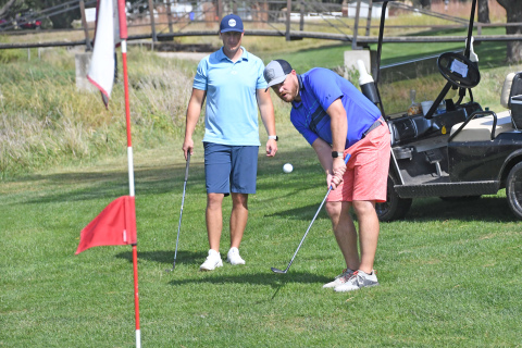 Brad Kell chips toward the hole while Adam Darbro looks on.