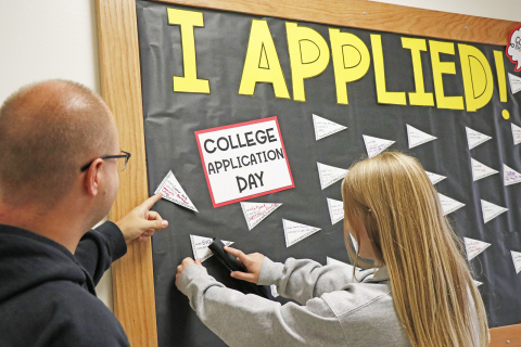 Students who have applied to a post-secondary school or other opportunity, like Eva Fahrnbruch (right) were invited to staple a flag to this board outside the counseling office.