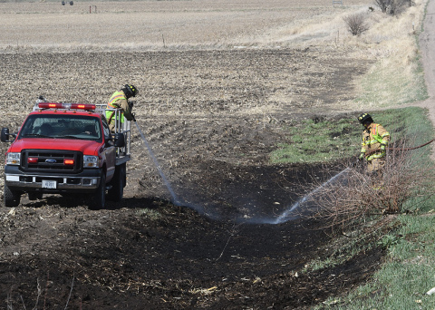 Two Aurora firefighters pour out water from hoses on burned ground after a ditch fire on S Road April 12. Fire Chief Tom Cox said the fire was started by lingering embers from before the burn ban and urged area residents to be vigilant even after fires are put out.