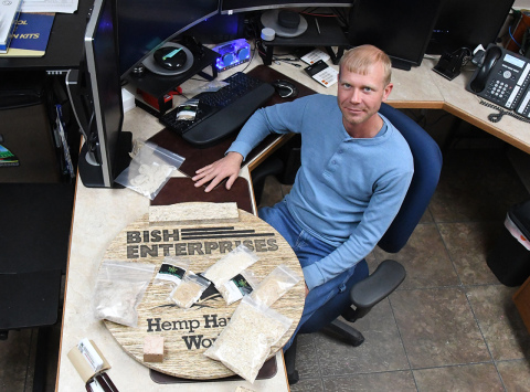 Andrew Bish, COO of Bish Enterprises and CEO of Hemp Harvest Works, shows in his Giltner office some of the products that can be made with hemp on top of a sign made of hemp wood. Blocks, absorbant, feed and other uses for hemp could foster growth of the farming market in the future, stated Bish.