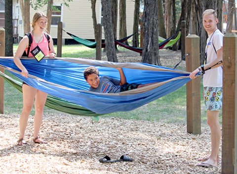 A couple of Big Campers introduce Little Camper, Brae to one of the hammocks at the beginning of Operation Shine Camp June 9 at Covenant Cedars Bible Camp near Hordville. 