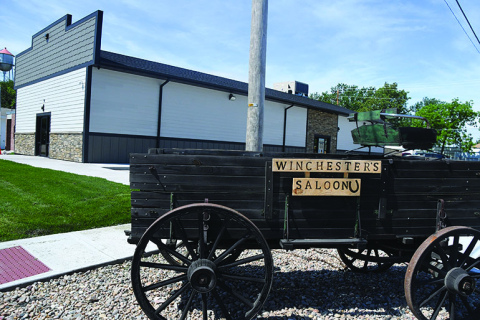 A wagon with the name of the new restaurant in Phillips sits next to the structure itself with the Phillips water tower in the distance. The saloon had a soft opening May 3 and will host a grand opening June 13 at 5:30 p.m.