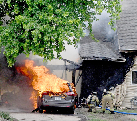 Flames erupt from a vehicle in the driveway of an L Street home Friday morning in Aurora.