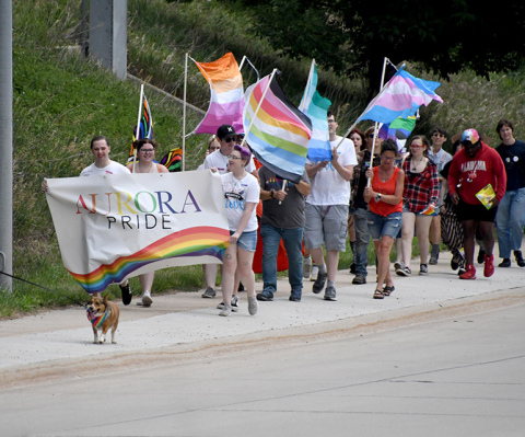 A group of approximately 40 people carried a banner and waved rainbow-colored flags along Highway 14 during the third annual Pride march Saturday in Aurora.