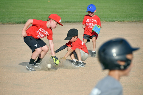 The red team’s Jett Hanna (left) and Liam Loveland (middle) help one another corral a grounder up the middle with some help from their teammate, Hoyt Anderson, in the background.