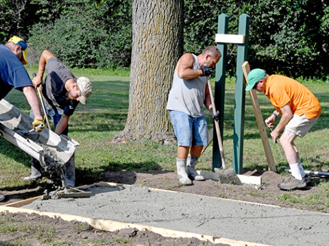 A crew works to pour the concrete tee pad for one of the holes for the new Streeter Park disc golf course in Aurora. At right is former Aurora resident Harry Eckerson, who proposed the course to the city to add to the existing one at Refshauge Park. 