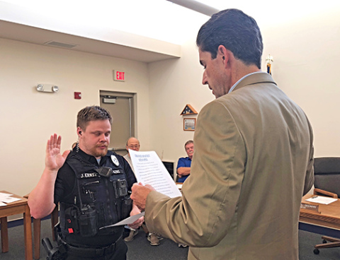 Joseph Ernst, left, is sworn in as a new Aurora police officer by City Attorney Ross Luzum.