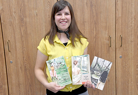 Author Katie Roszhart proudly holds three of her books from her book series, Naioth Adventures.