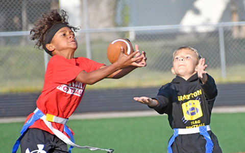 Aurora Red 2nd grader Kanon Dillon snags an interception over Hampton’s Talon Goos during flag football action Saturday morning. 