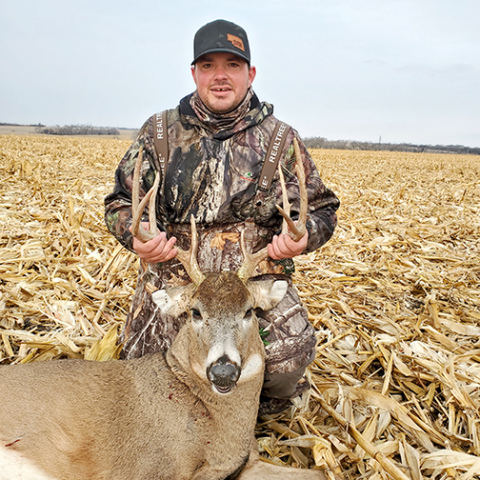 Jon Bruner poses in a cornfield with a large buck he took with a rifle last season near Alvo. 