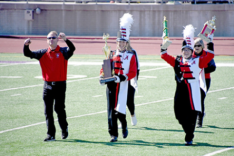Band directors and drum majors hold their heads high as they showcase the hardware they won, moments after hearing the results at Saturday’s Harvest of Harmony competitions.