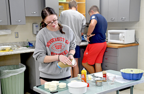 Kylee Young makes monkey bread in Senior Seminar class on Thursday while Sam Wishman and Korbin Stump work on another part of breakfast in the background. 